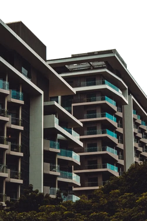 Torres residenciais com varandas de vidro e árvores em primeiro plano